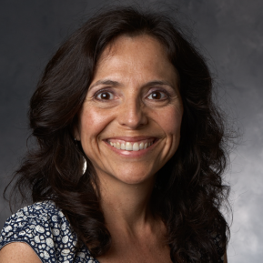 Image of women with black hair wearing a pattern blue shirt, in front of a gray background