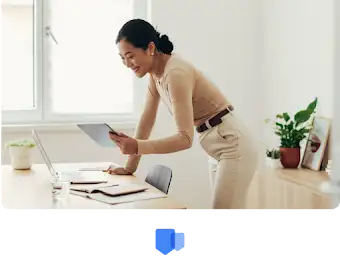 Une femme penchée sur son bureau regarde ses distinctions et récompenses sur sa tablette.