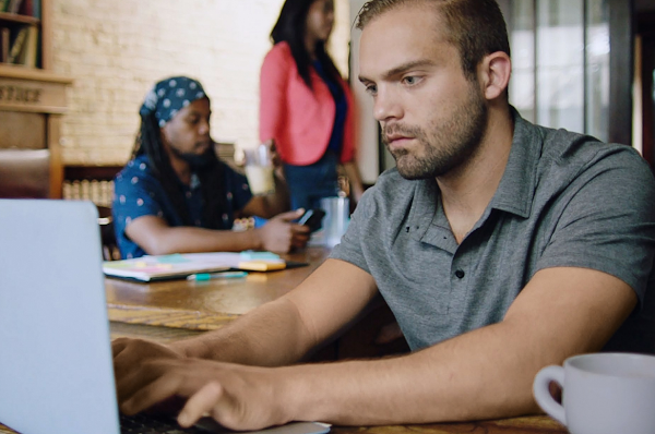 A man sits and intently works on a laptop