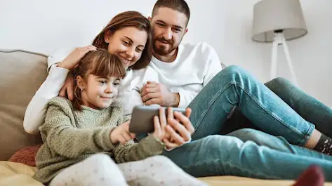 a father, mother and daughter watching a discovery  show on one smartphone.