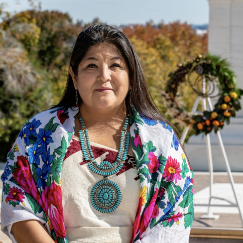 Indigenous Woman woman in traditional dress stands outside in the sun