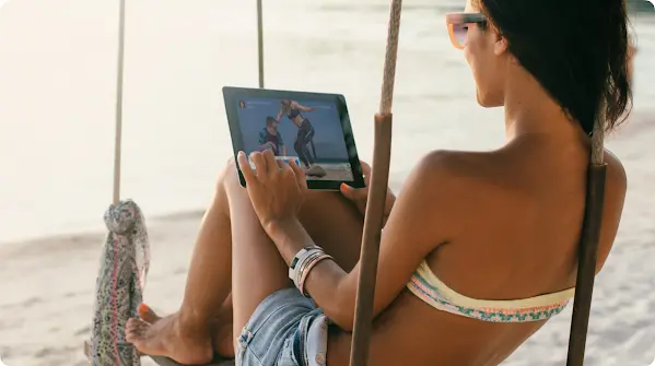 Seorang perempuan sedang melihat tablet di pantai