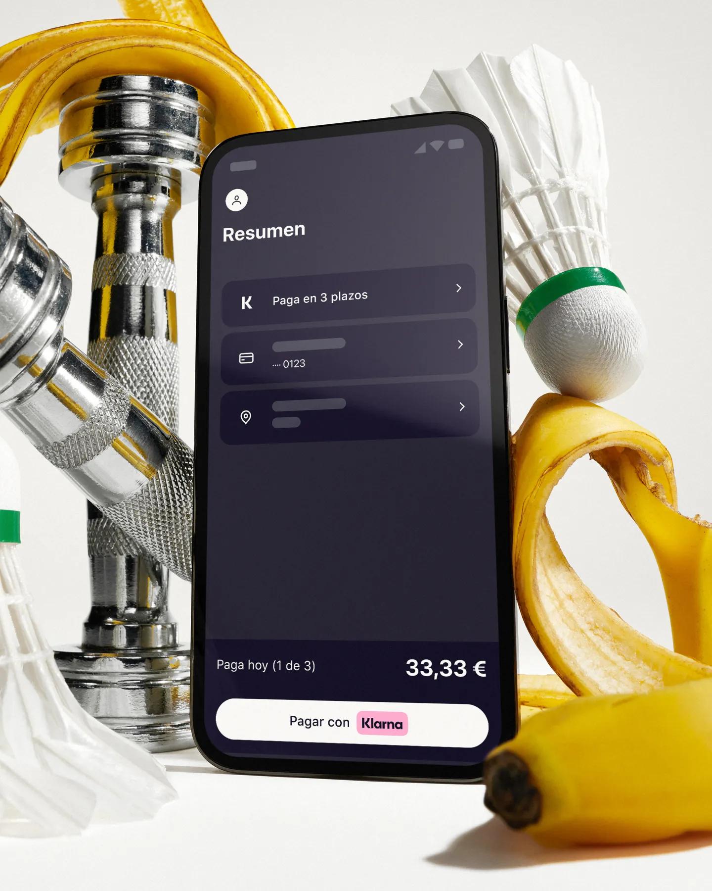 Phone with klarna app in front of artistically styled sport atributes