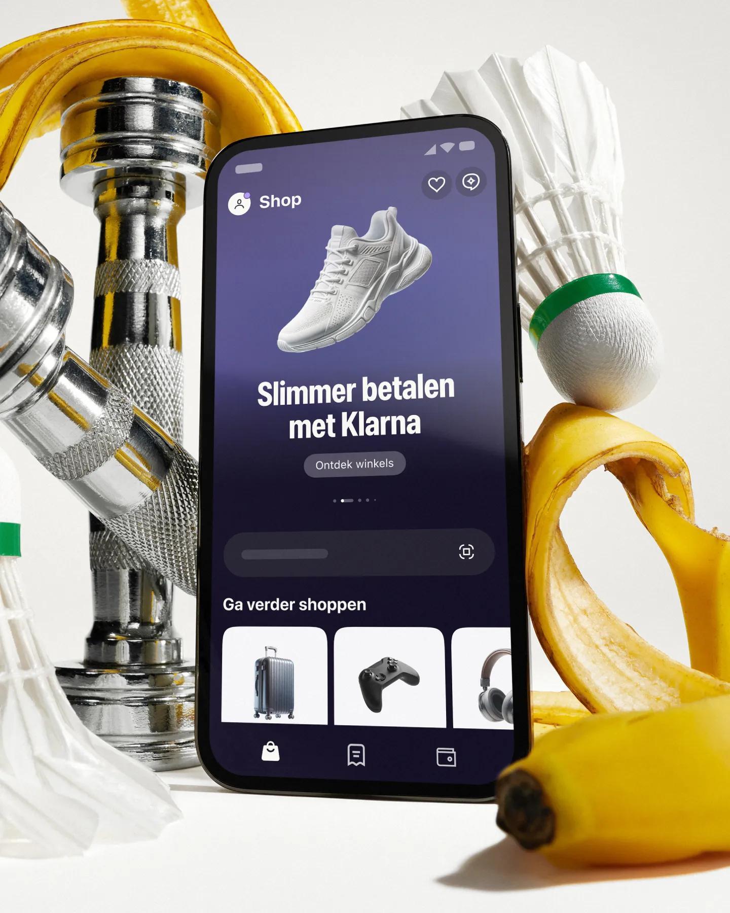 Standing phone with Klarna app open in front of workout gear