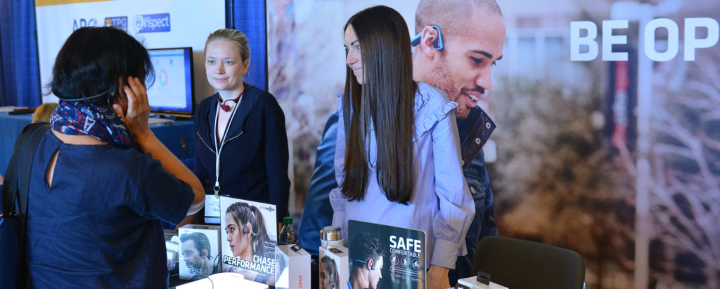 Woman wearing headphones at AfterShokz exhibitor booth