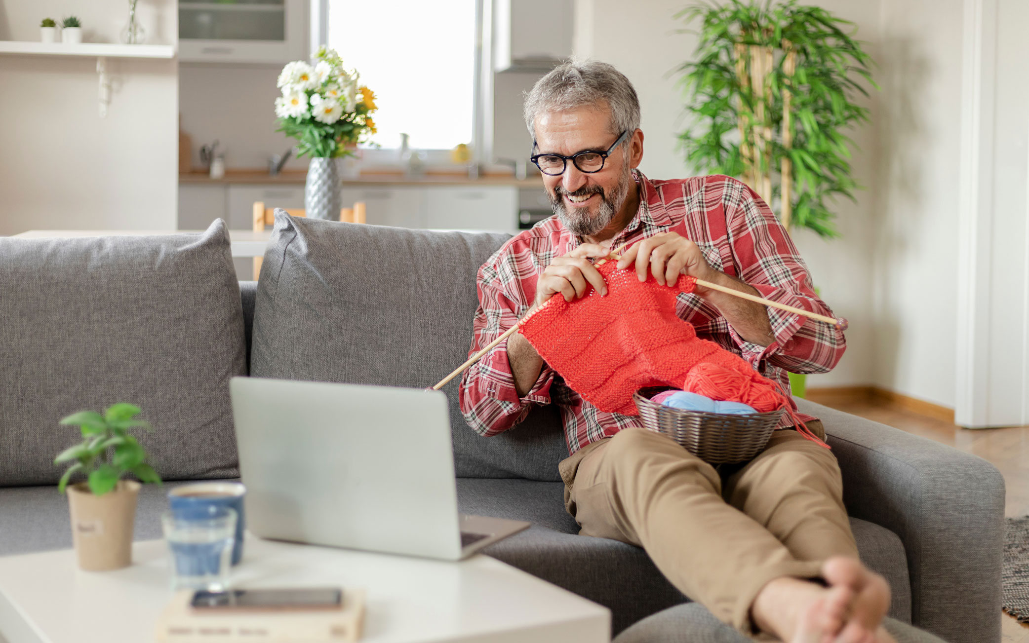 person knits while watching something on their laptop