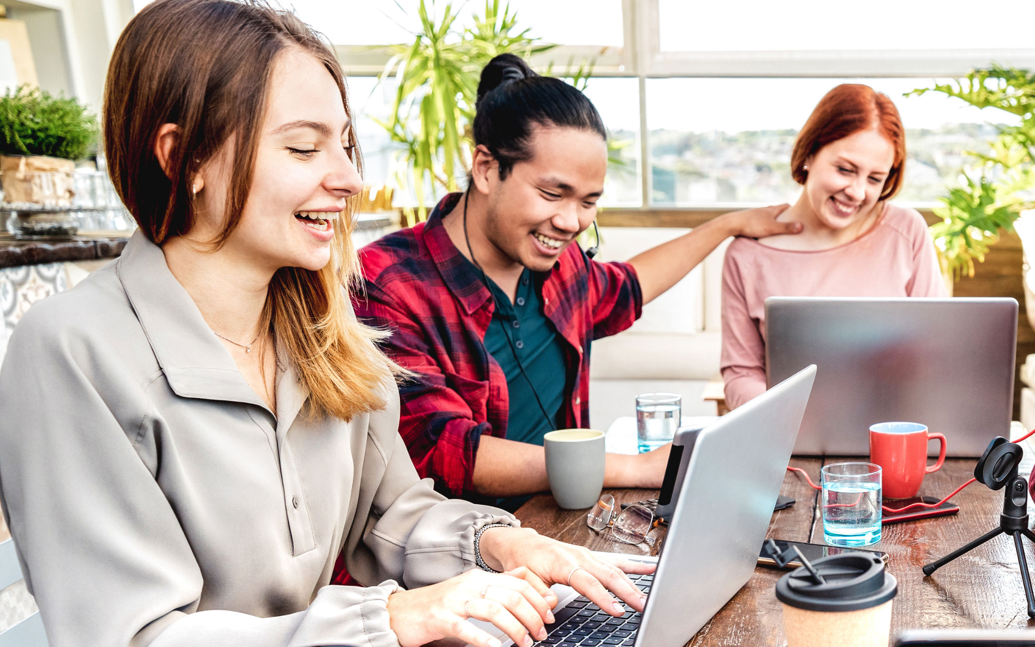 three people sit together looking at laptops