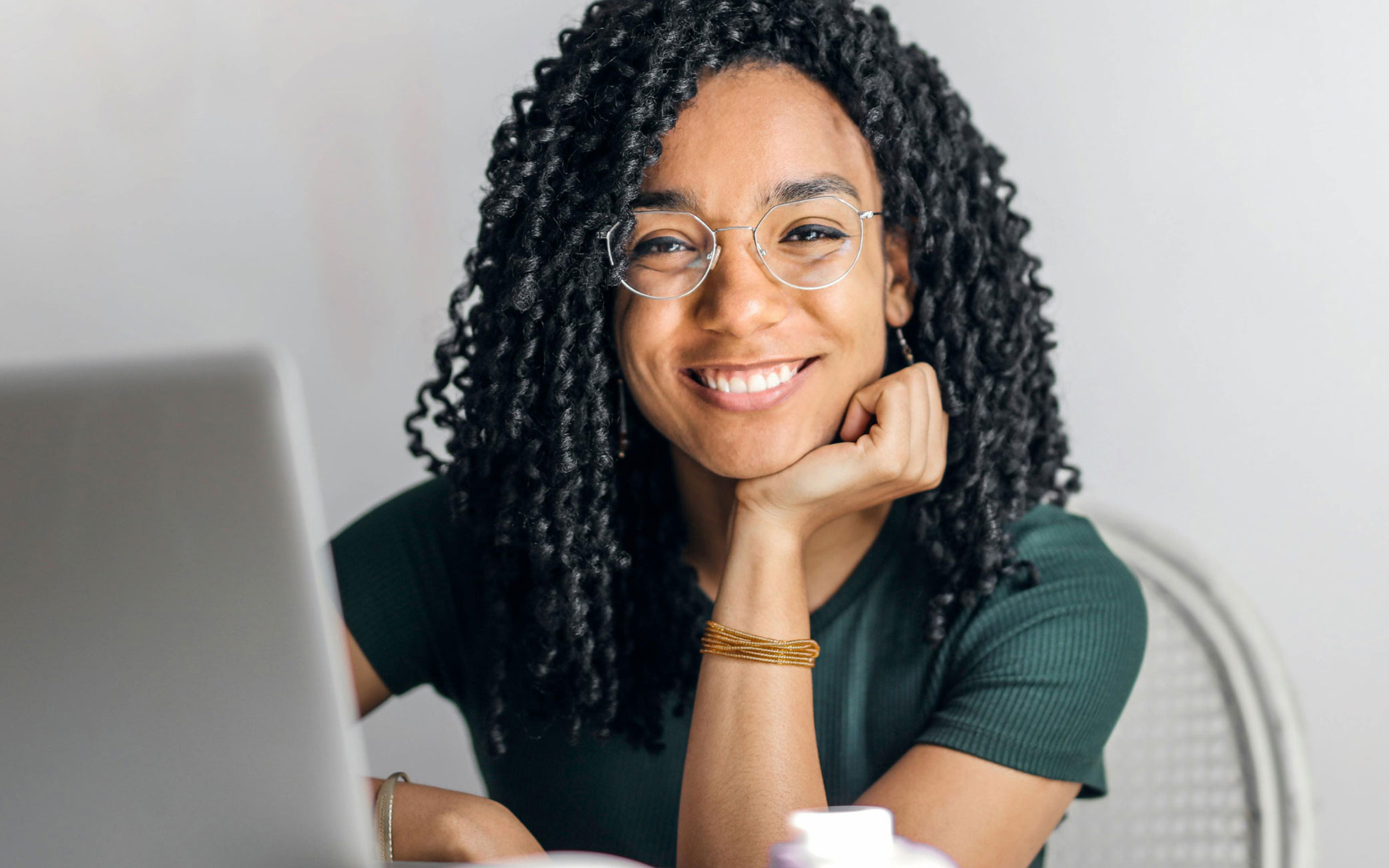 person smiles from behind laptop