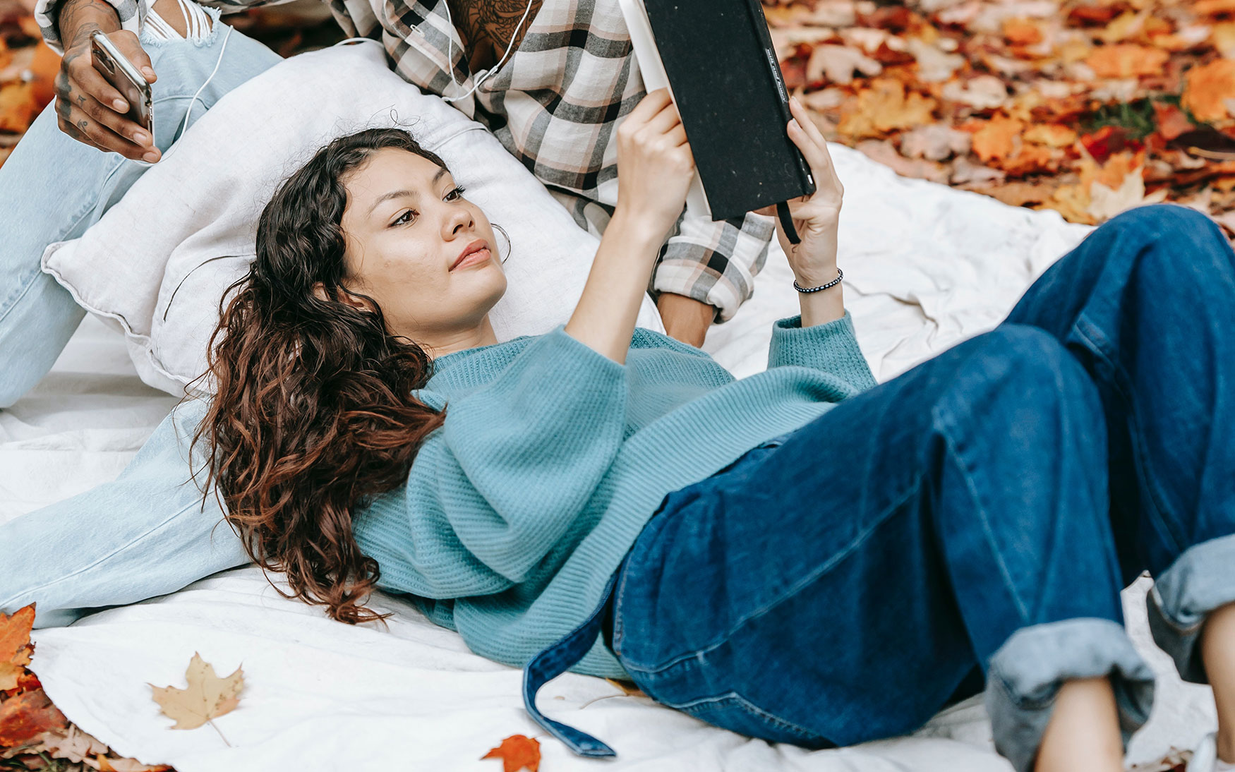 person lays on ground and reads book