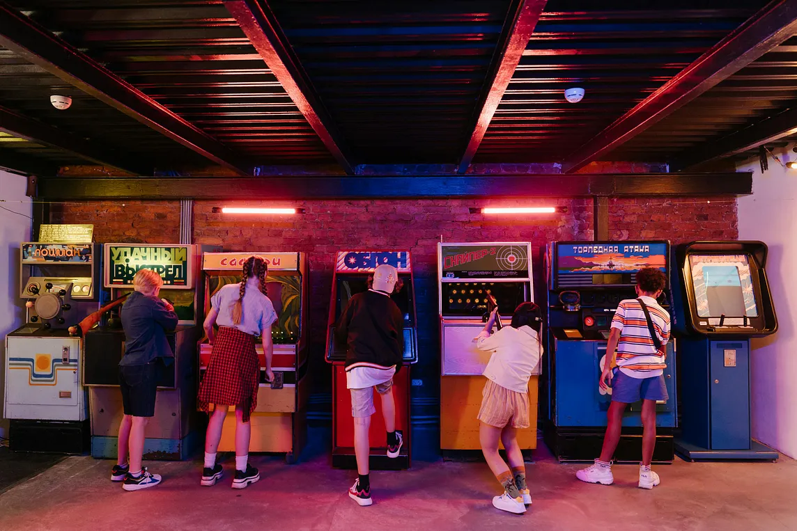 Five kids playing arcade style video games in an arcade or restaurant.