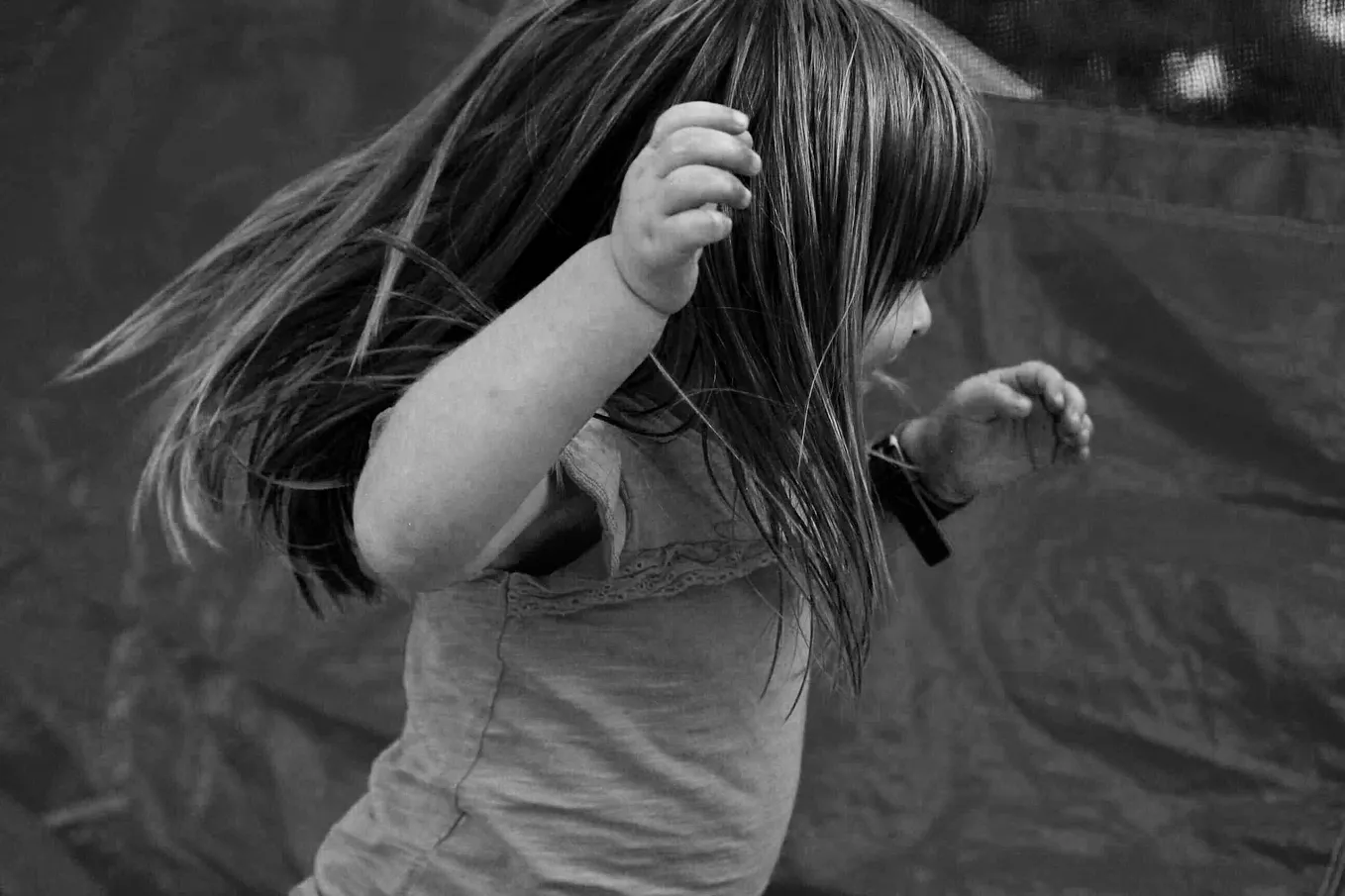 A photo of a little girl shows her in motion, runing and possibly twirling happily as she plays.