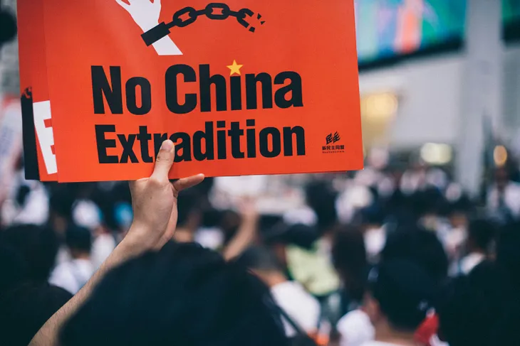 A street protester in Hong Kong holds up a sign that reads, “No China Extradition.”