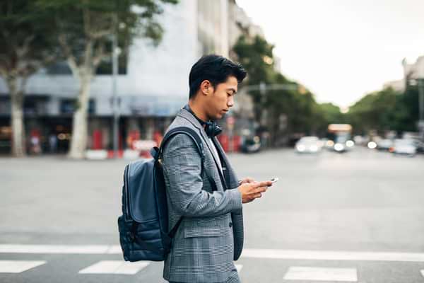 Man walking on street path working on mobile phone