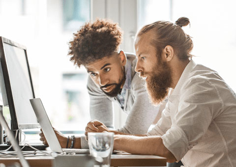 Two men looking at laptop in an office space 