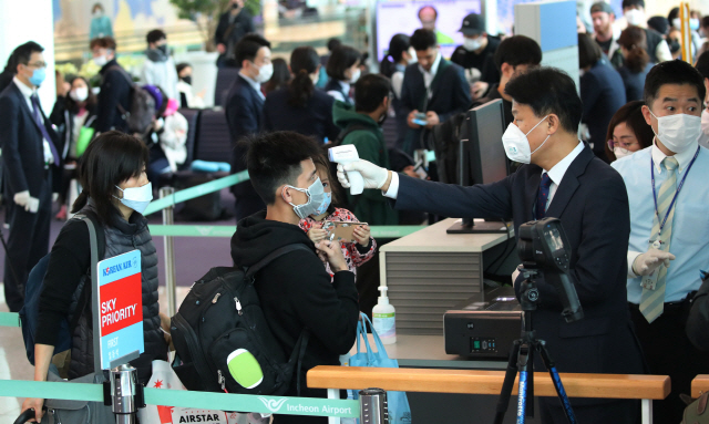 대한항공 관계자들이 28일 인천국제공항 제2터미널 탑승구에서 로스앤젤레스(LA)행 KE017편 탑승 승객에게 열화상 카메라와 휴대용 체온계로 발열 체크를 하고 있다. 대한항공은 인천공항을 출발하는 미주 노선 전편에 대한 발열 체크를 의무화하는 한편 추가적인 기내 소독을 진행하기로 했다./영종도=권욱기자