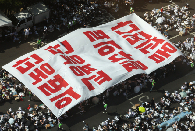 대한의사협회(의협)의 주도로 개원의와 일부 의대 교수들이 집단휴진에 나선 18일 오후 서울 영등포구 여의대로에서 열린 전국 의사 총궐기대회에서 의사들이 '의료농단' 등 문구가 적힌 대형현수막을 펼치고 있다. 연합뉴스