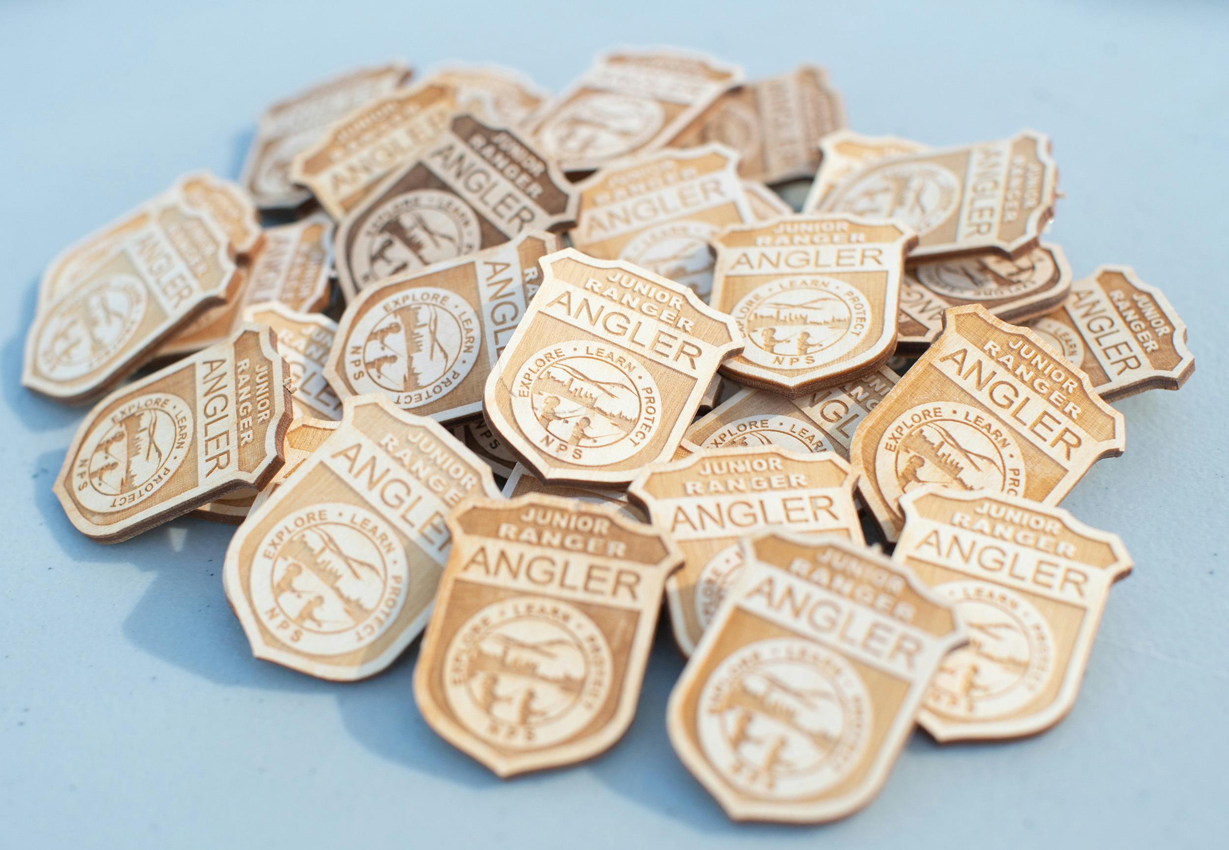 Wooden badges with text that reads: Junior Ranger Angler