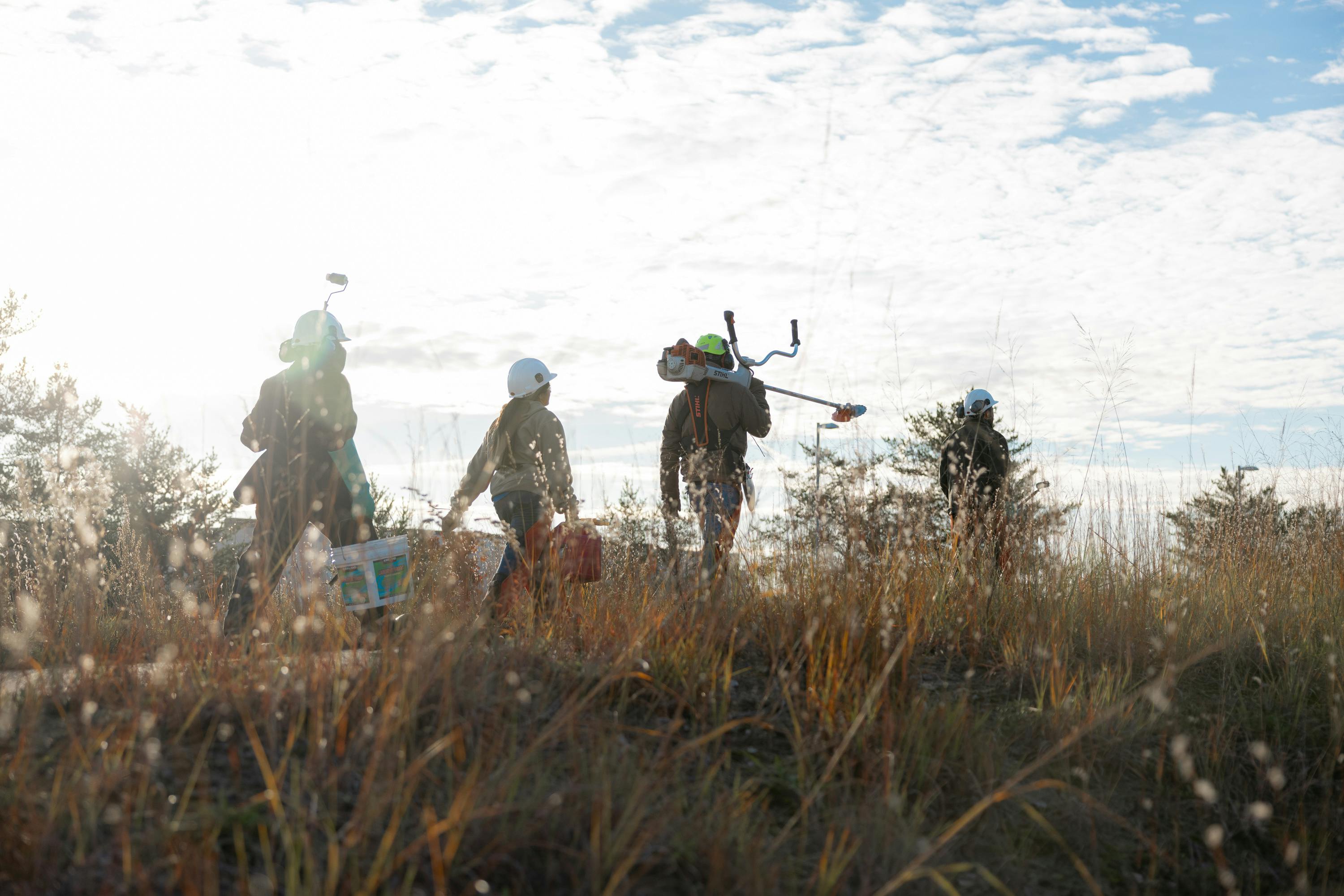 A group of people holding tools walking along a path