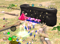 A group of Blue Pikmin breaking down a black wooden gate in Creator's Garden.