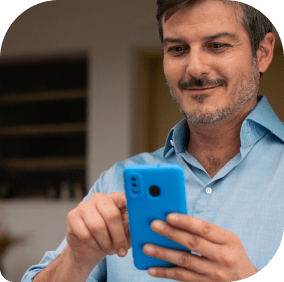 Homem sorrindo olhando para celular nas mãos