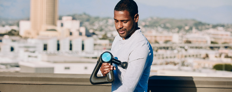 A man uses the Therabody G4 Theragun Pro on his arm.