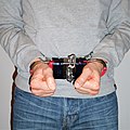 Closeup of an individual in handcuffs with a handcuff cover, front parallel position.