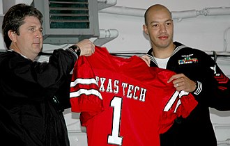 Mike Leach presenting Air Traffic Controller 1st Class Mitchel Deshotel a team jersey and making him an honorary team captain for the 2004 Holiday Bowl