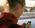 Young woman viewing screen and typing on mobile phone