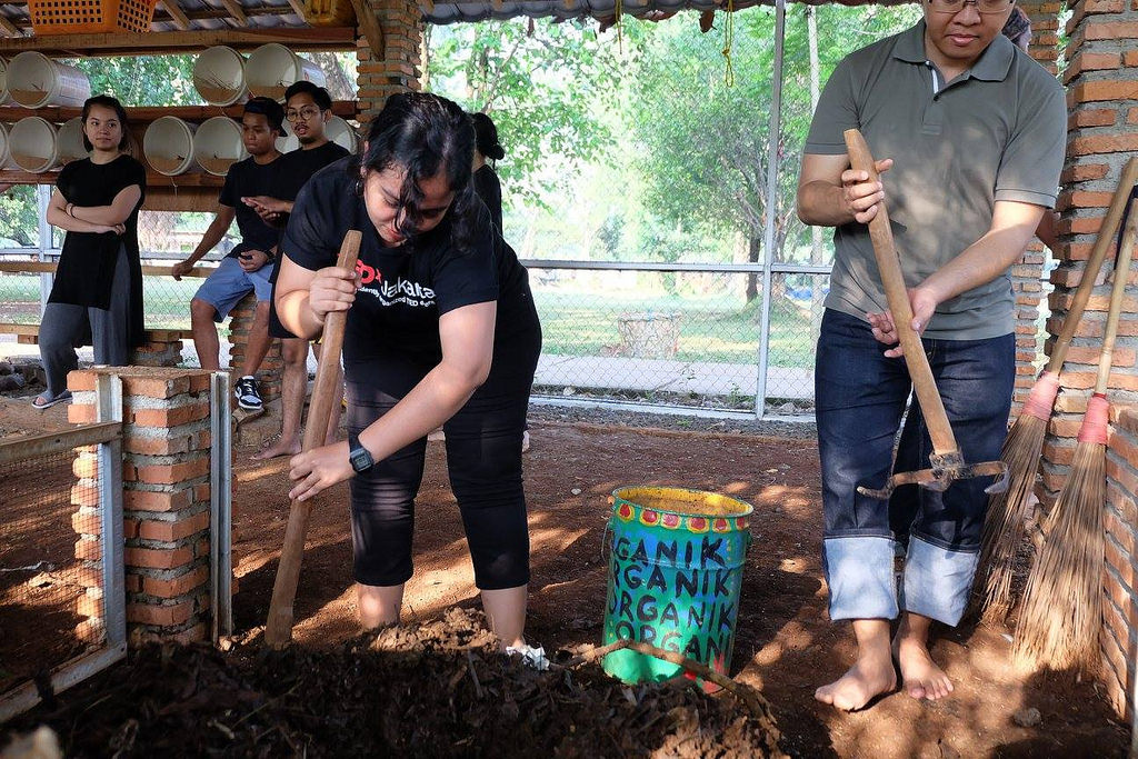 A woman leans down to till earth and compost.