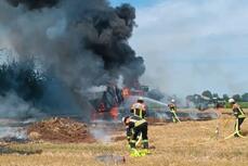 Eine brennende und rauchende Ballenpresse auf einem Feld