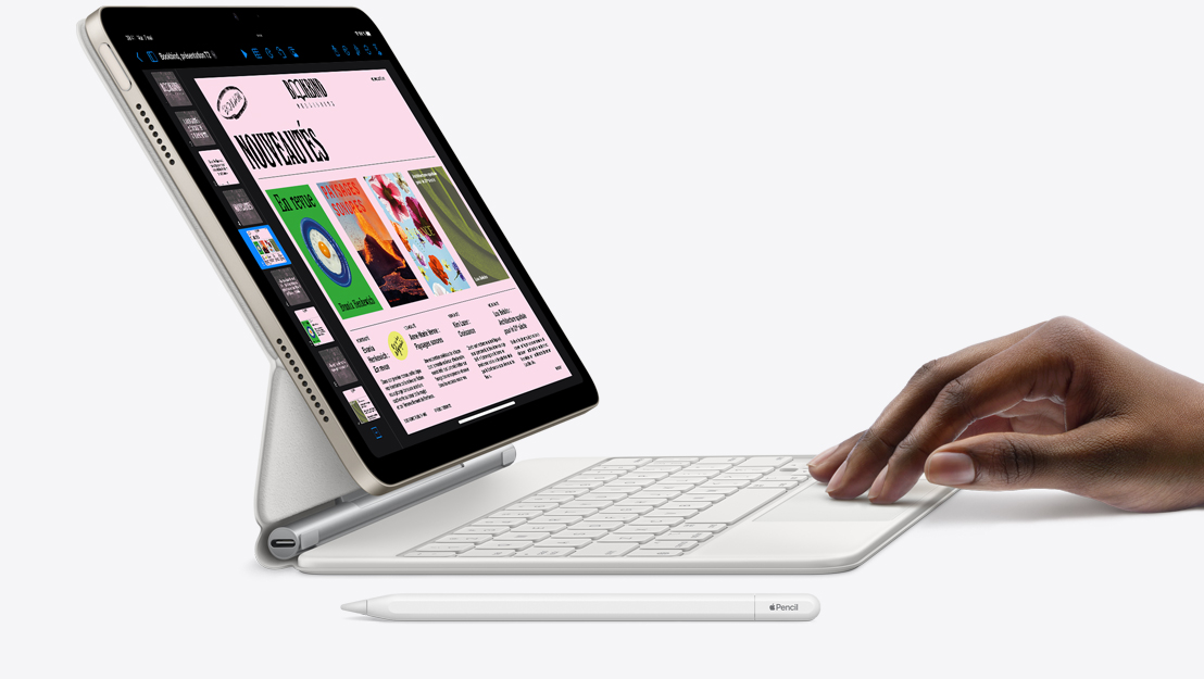 Vue de biais d’un iPad Air affichant l’app Keynote, attaché à un Magic Keyboard avec une main sur le pavé tactile et un Apple Pencil posé à côté.