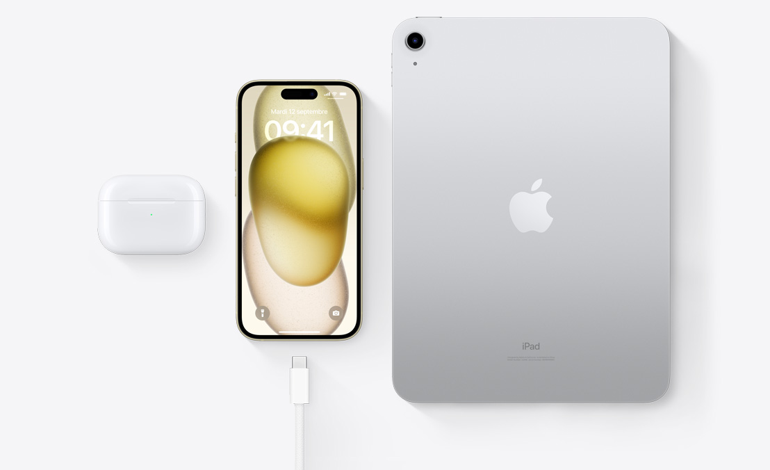 Vue en plongée des AirPods Pro, d’iPhone 15 et d’iPad, trois appareils dotés d’un connecteur USB-C qui peuvent être rechargés avec le même câble.