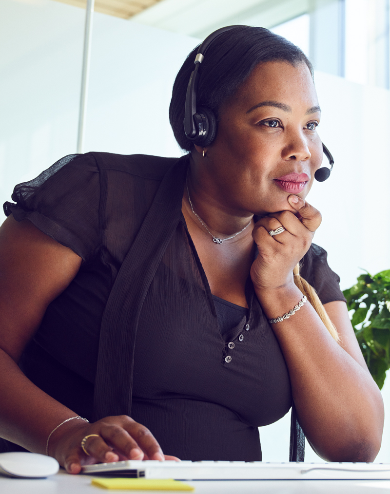 Een Apple Support Advisor met headset kijkt tijdens een gesprek geconcentreerd op haar scherm.