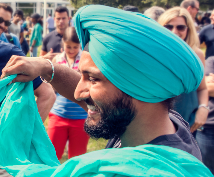 Fotografia de um homem a sorrir, a usar um turbante e a enrolar o turbante de outra pessoa.