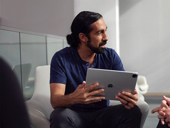 An Apple Operations and Supply Chain employee holding an iPad and looking to the side.