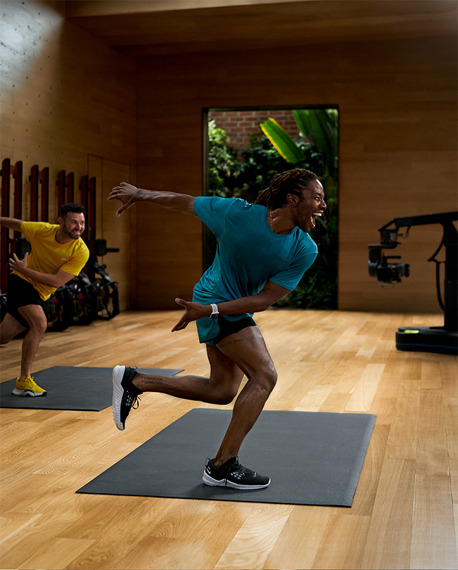 Due trainer Apple Fitness  che tengono un corso davanti ad alcune videocamere in uno studio di registrazione. 