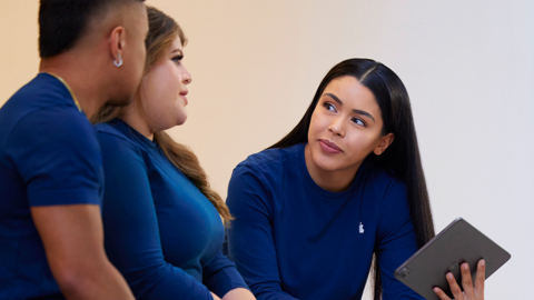  Trois membres de l’équipe Apple parlent ensemble, et l’un tient un iPad.