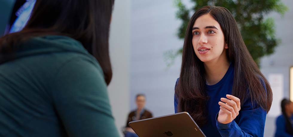 Serene, un iPad à la main, discute avec une cliente.