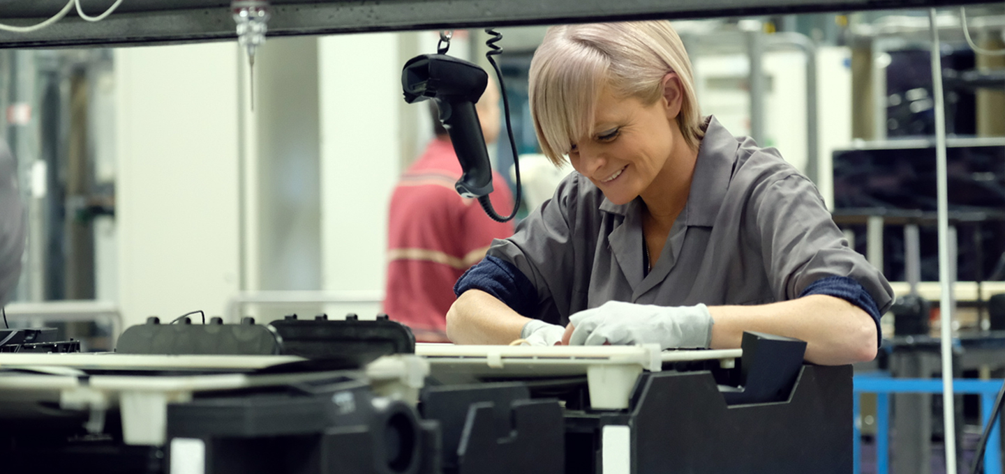 Zwei Apple Mitarbeiter prüfen Mac Aluminiumgehäuse in einer Apple Fertigungsstrasse zum Anodisieren von Titan.