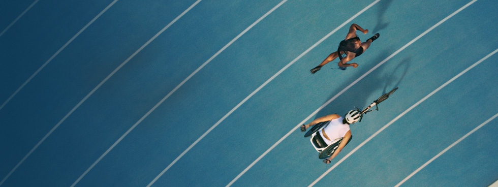 Two athletes about to race each other on the track. One of them has a prosthetic leg.