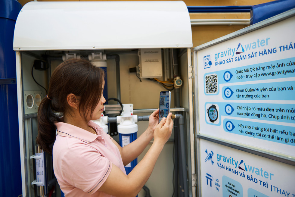 Une élève utilise un iPhone pour scanner un QR code figurant sur un panneau d’affichage de Gravity Water au sein de l’École primaire et secondaire Vay Nua pour les minorités ethniques.