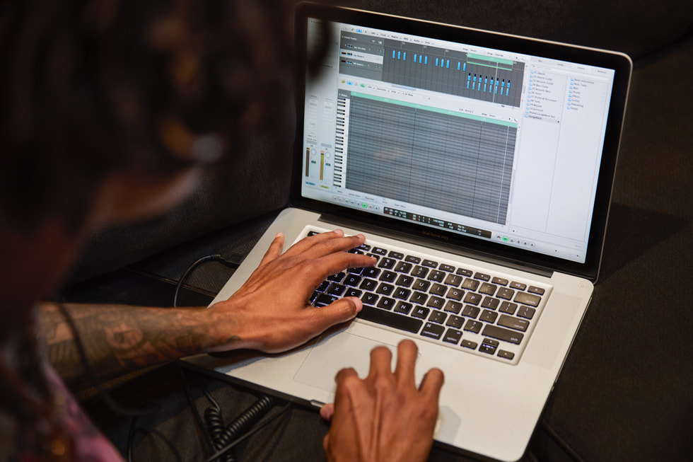 Primer plano de Fresh Ayr usando Logic Pro en su MacBook Pro para producir una pista.