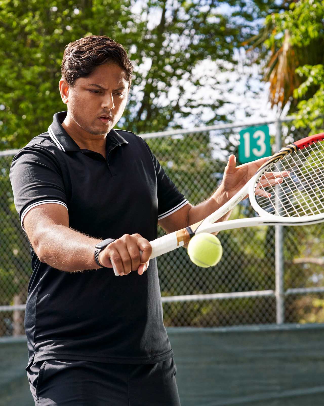 Sahai takes a backhand swing at a tennis ball while on the court.