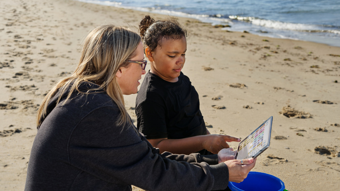 Jay Ashburn (right), uses Proloquo on his mother’s iPad to communicate with her at Virginia Beach.