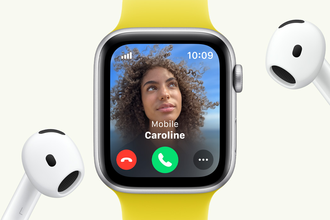 „Apple Watch SE“ rodomas gaunamas skambutis, o šalia „AirPods“ ausinės