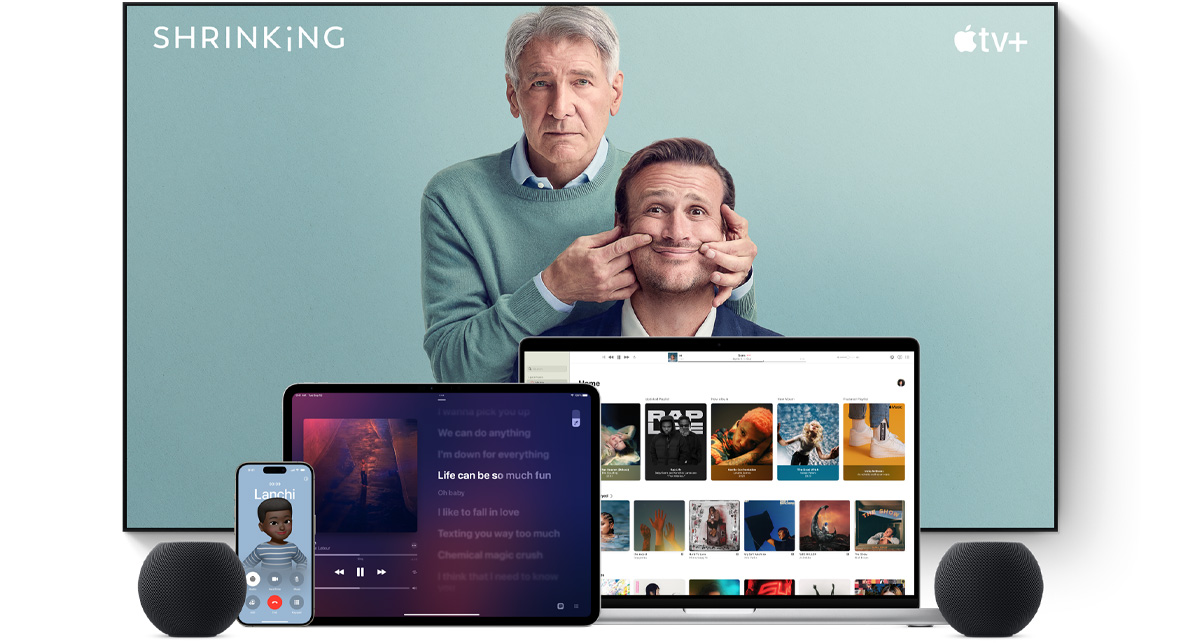 Large flat screen television showing two male characters from the Apple TV  series shrinking. A MacBook Pro, an iPad, an iPhone, and a Midnight HomePod mini are arranged in front.