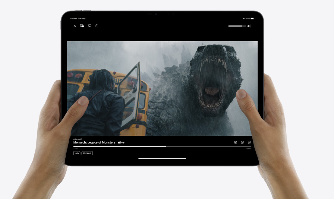 Sepasang tangan memegang iPad Pro yang menampilkan aplikasi TV sedang memutar acara "Monarch: Legacy of Monsters."