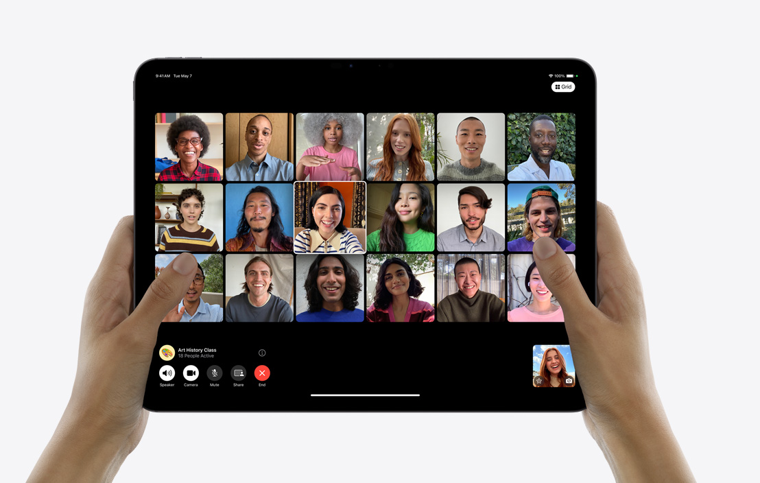 Sepasang tangan memegang iPad Pro yang menampilkan panggilan FaceTime grup.