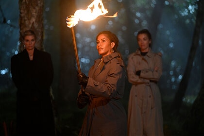 Sheree holds up a torch in the middle of the woods