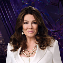 Lisa Vanderpump wearing a white pantsuit while in a purple room overlooking LA.